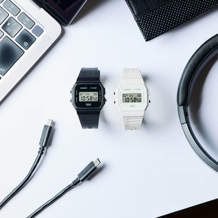 Casio Collection F-91WB-7AEF must-have minimalist digital watches in black and white beside laptop and accessories.