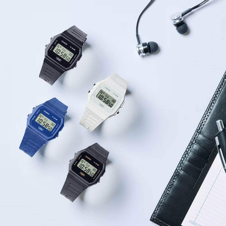 Casio Collection F-91WB-2A1EF neljällä eri värillä pöydällä, digitaalinen rannekello, moderni ja minimalistinen tyyli.