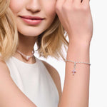 Nuori nainen, jolla on päällään Thomas Sabo Charm Club Pink Cross Hela 2032-051-9 -riipus rannekorussa.