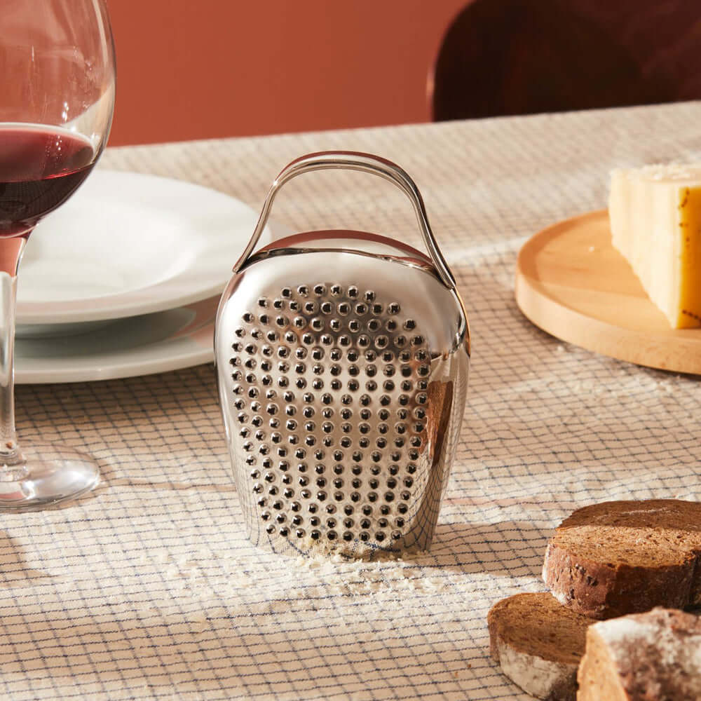 Alessi Cheese Please juustoraastin CHB02 kauniilla pöydällä, taustalla viini ja juustot.
