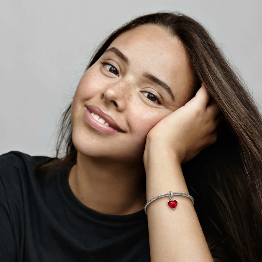 Nuori nainen hymyilee käsi poskella, ranteessa Pandora Mickey & Minnie Mouse Murano Glass charm hela 792522C01.